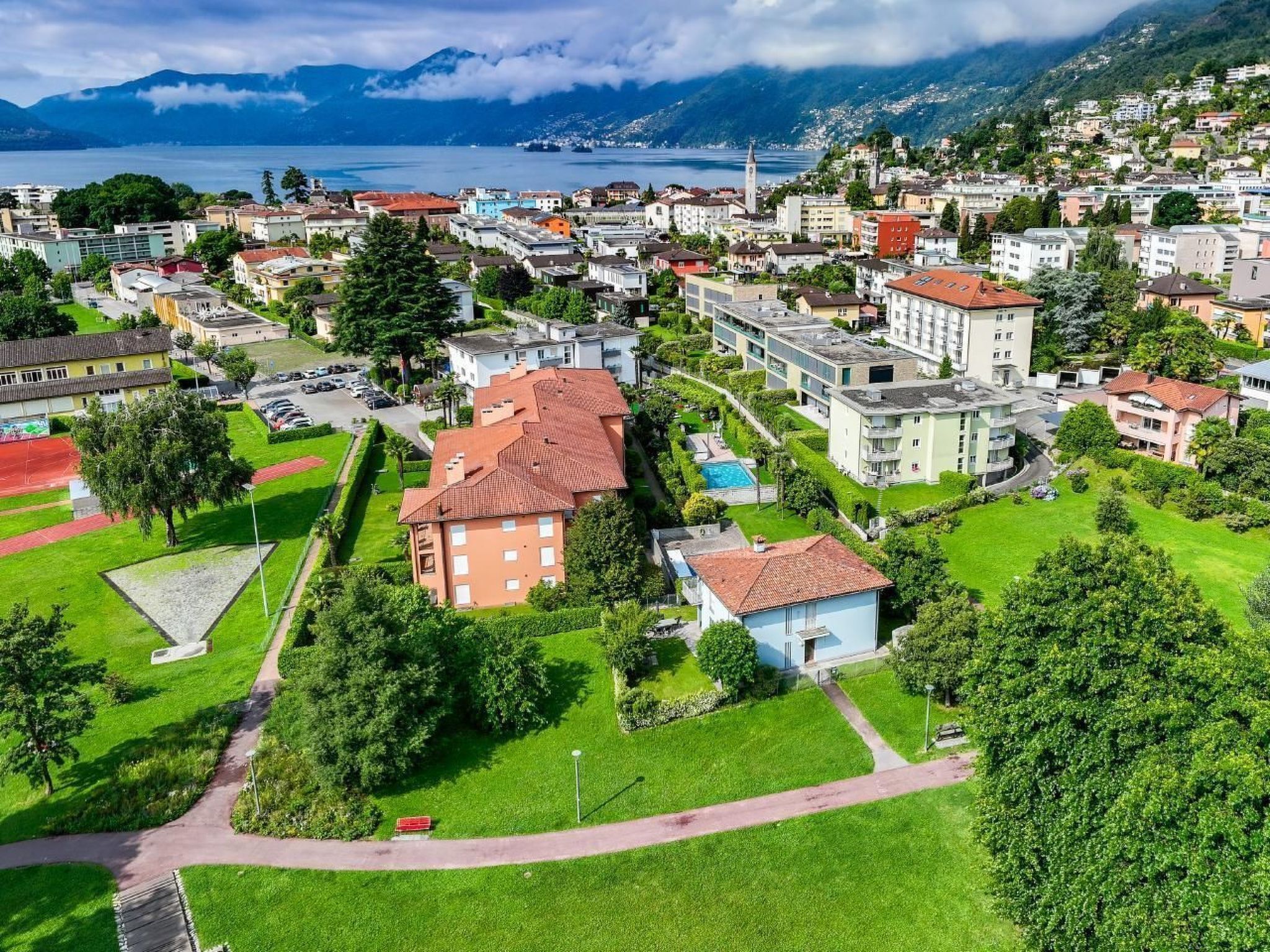 Une vue aérienne d’un quartier résidentiel, avec des immeubles, des espaces verts et un lac en arrière-plan.