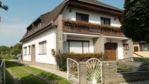 A two-story house with a sloped roof, a balcony with red flowers, and a gated entrance. - mit Swimmingpool für 10 Personen by Interhome (Balatonkeresztur)
