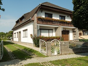 Ein zweistöckiges Haus mit einem geneigten Dach, einem Balkon mit roten Blumen und einem verschlossenen Eingang.