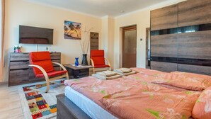 A bedroom with a bed, two red chairs, a desk, a TV, and a painting on the wall. - mit Swimmingpool für 10 Personen by Interhome (Balatonkeresztur)