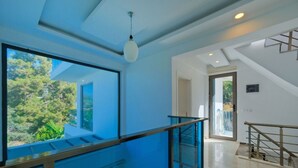 Un interno moderno con ringhiera in vetro, una scala e vista sul verde circostante.