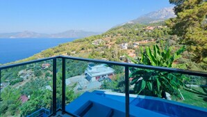 Un balcone con vista libera sul paesaggio costiero, che include una distesa d'acqua e montagne in lontananza.