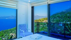 Una camera da letto moderna con un letto grande, un'area salotto e un balcone con vista panoramica.