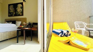 Une chambre d’hôtel avec un lit, une petite table sur laquelle se trouve une boisson, une chaise jaune et une fenêtre avec des rideaux.