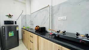 Une cuisine dotée d’un plan de travail noir, d’un four à micro-ondes, d’un réfrigérateur, d’un évier et d’une cuisinière à gaz.