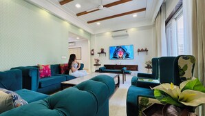 Un salon moderne avec des canapés de couleur turquoise, une table basse et un téléviseur fixé au mur.