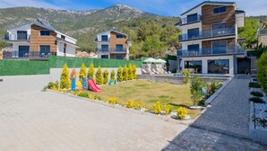 A modern residential complex with multiple two-story buildings, a playground, and a swimming pool.