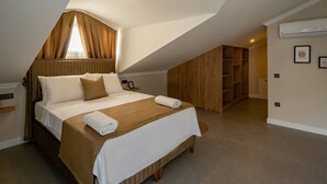 Un dormitorio con techo inclinado, una cama con cabecera marrón y un armario de madera.