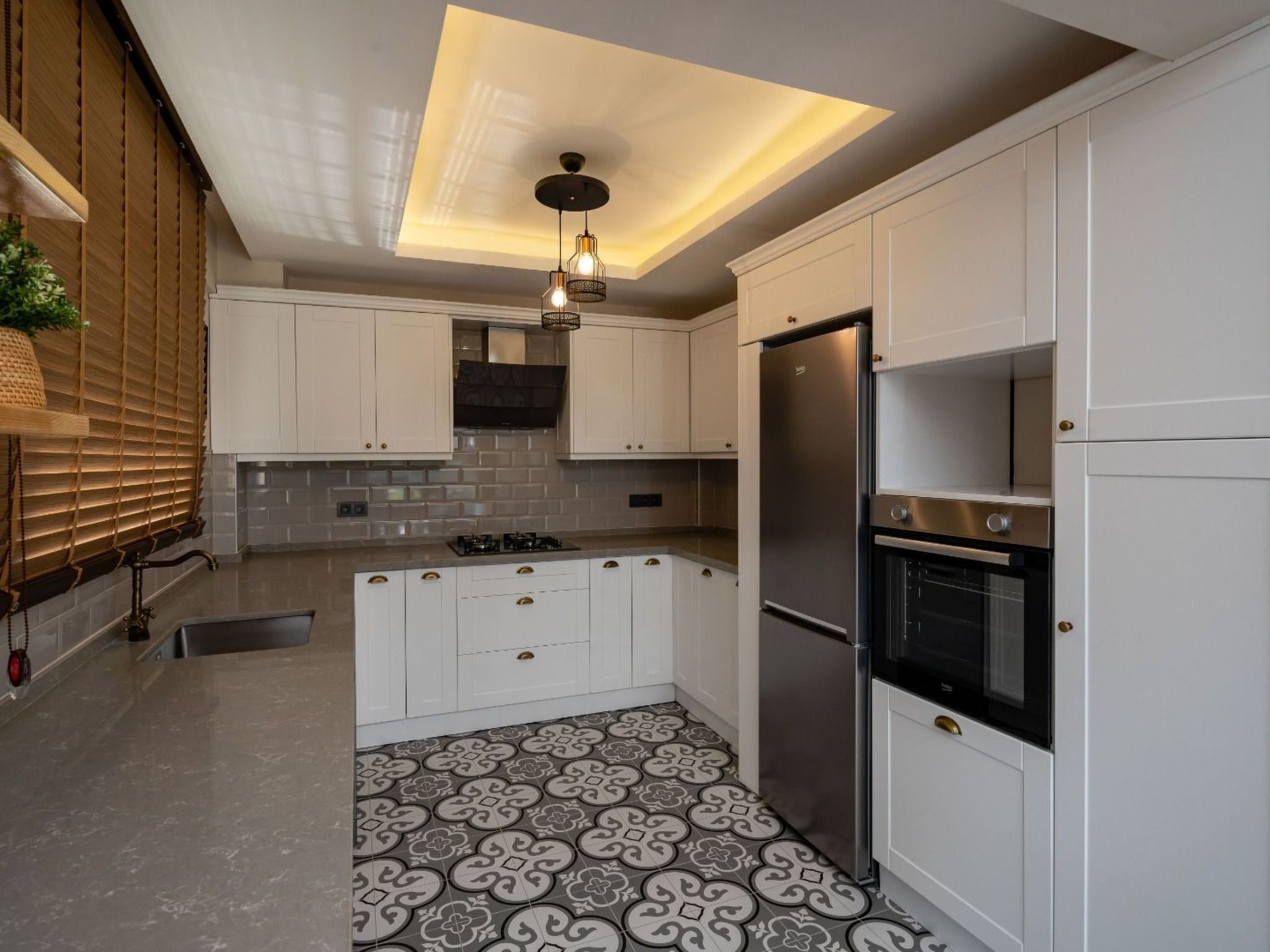 Una cocina moderna con armarios blancos, un refrigerador de acero inoxidable y un piso de baldosas estampadas.
