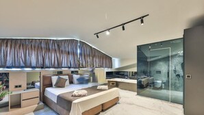 A modern bedroom with a large bed, bedside tables, a built-in desk, and a glass-enclosed shower area. - Zentrale in Fethiye by Interhome (Ölüdeniz)