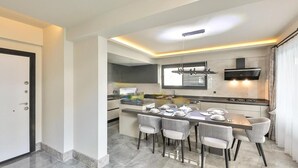 A modern kitchen with a dining area, featuring a central island, pendant lighting, and a built-in stove. - Zentrale in Fethiye by Interhome (Ölüdeniz)