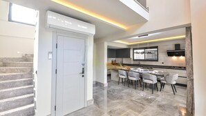 A modern kitchen with a dining area, a staircase, and a door. - Zentrale in Fethiye by Interhome (Ölüdeniz)