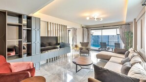 A modern living room with a flat-screen TV, a sofa set, a coffee table, and a built-in bookshelf. - Zentrale in Fethiye by Interhome (Ölüdeniz)