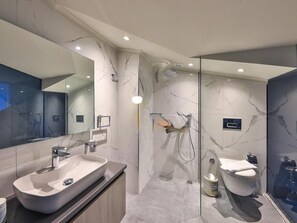 Un bany modern amb un mirall gran, un lavabo independent, una dutxa amb envàs de vidre i un vàter.