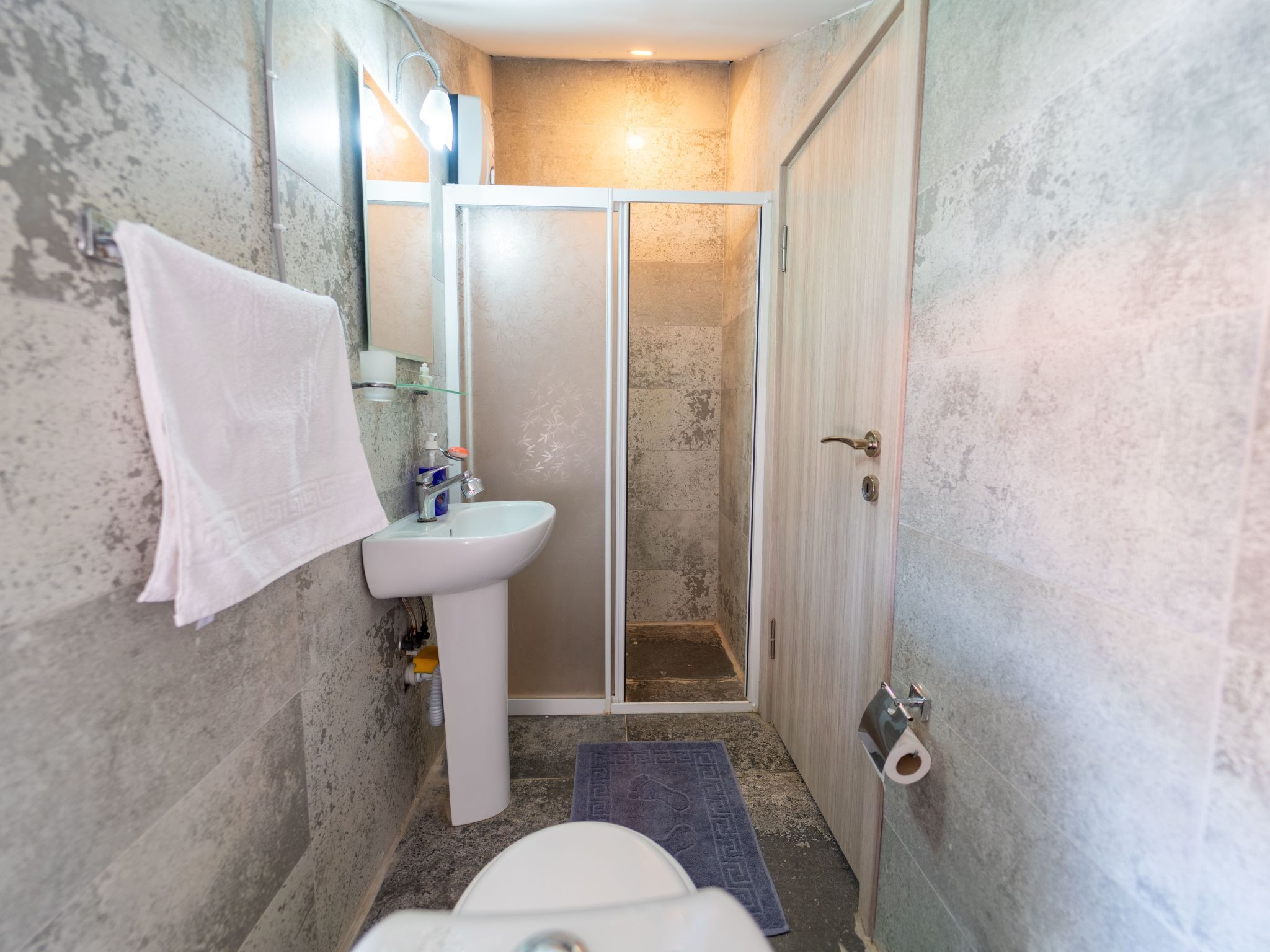A bathroom with a white sink, a glass shower enclosure, and a toilet.
