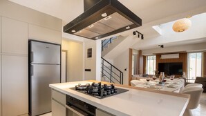 A modern kitchen with a central island, built-in oven, and stainless steel appliances.