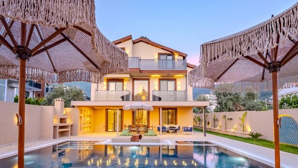 A modern two-story house with a swimming pool, outdoor seating, and a balcony.