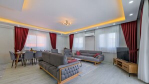 A modern living room with a sofa, armchairs, a dining table, and a TV. - Villa in der Natur by Interhome (Ölüdeniz)