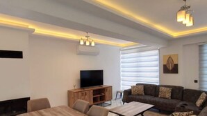 A modern living room with a wooden dining table, a sofa, and a TV. - Villa in Ölüdeniz für Familien 8 P by Interhome (Ölüdeniz)