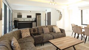 A modern living room with a sectional sofa, a coffee table, and a dining area with chairs. - Villa in Ölüdeniz für Familien 8 P by Interhome (Ölüdeniz)