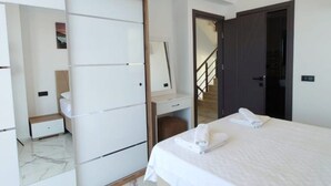 A modern bedroom with a large bed, a wardrobe, a desk, and a mirror. - Villa in Ölüdeniz für Familien 8 P by Interhome (Ölüdeniz)