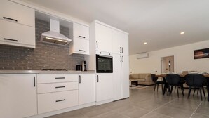 A modern kitchen with white cabinets, a built-in oven, and a gas stove.