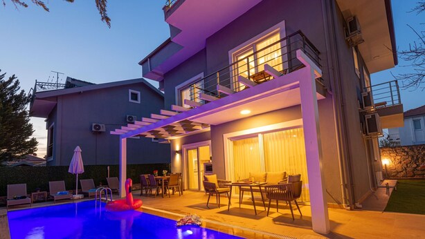 A modern two-story house with a swimming pool, outdoor seating area, and a covered patio.