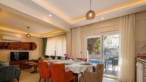 A modern living room with a dining area, a TV, and a kitchen.