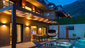 Una casa moderna con piscina, mobiliario exterior y un patio cubierto.