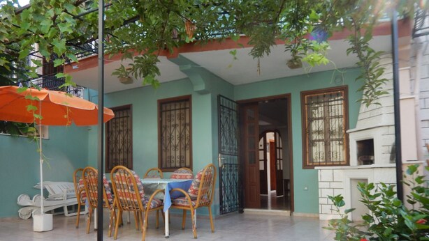 Une terrasse avec une table et des chaises, un mur en pierre et un petit espace cuisine extérieur.