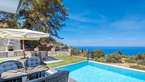 A swimming pool with a stone wall and a pergola with outdoor furniture. - Villa mit Infinitypool in Fethiye Faralya by Interhome (Ölüdeniz)