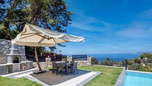 A patio with a stone fireplace, outdoor furniture, and a pool. - Villa mit Infinitypool in Fethiye Faralya by Interhome (Ölüdeniz)