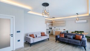 A modern living room with two sofas, a kitchen in the background, and a dining area with green chairs. - Villa mit Infinitypool in Fethiye Faralya by Interhome (Ölüdeniz)