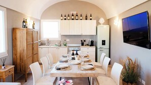 Una cocina moderna con armarios blancos, una mesa de comedor lista para seis personas y una estantería para vinos sobre la encimera.