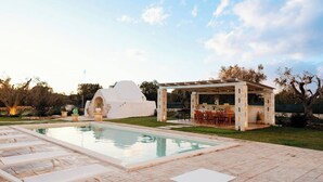 Un área de piscina con una pérgola y una estructura blanca.