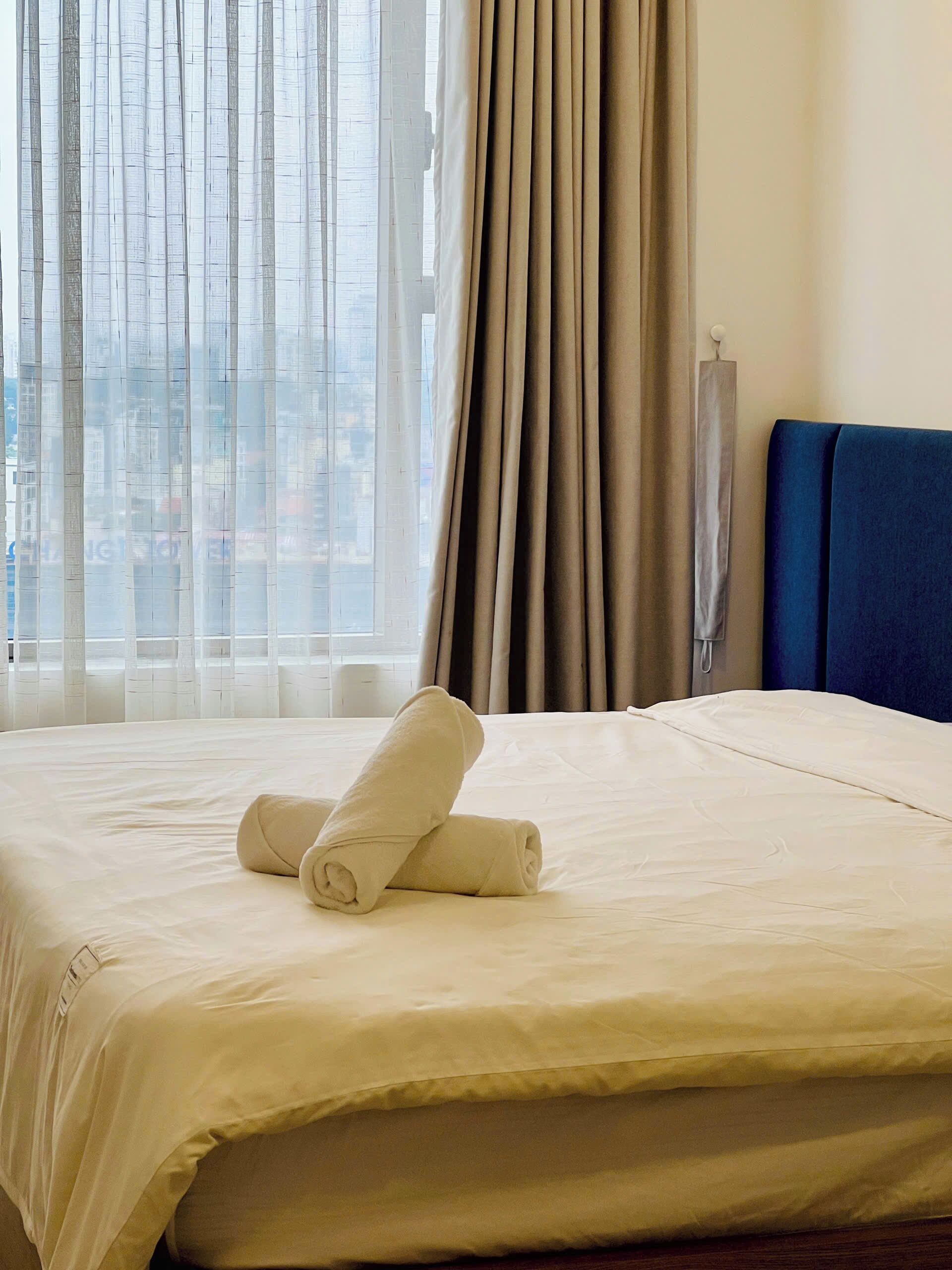 Une chambre d’hôtel avec un lit, une fenêtre avec des rideaux et une vue sur les bâtiments environnants.
