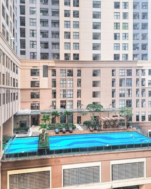 A high-rise building with a rooftop pool area, including lounge chairs and a covered seating area. - Spacious 4-bedroom condo with AC in soothing Thành phố Hồ Chí Minh (Thành phố Hồ Chí Minh)