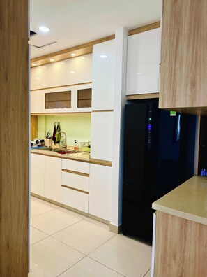 A modern kitchen with white cabinets, a black refrigerator, and a wooden countertop. - Spacious 4-bedroom condo with AC in soothing Thành phố Hồ Chí Minh (Thành phố Hồ Chí Minh)