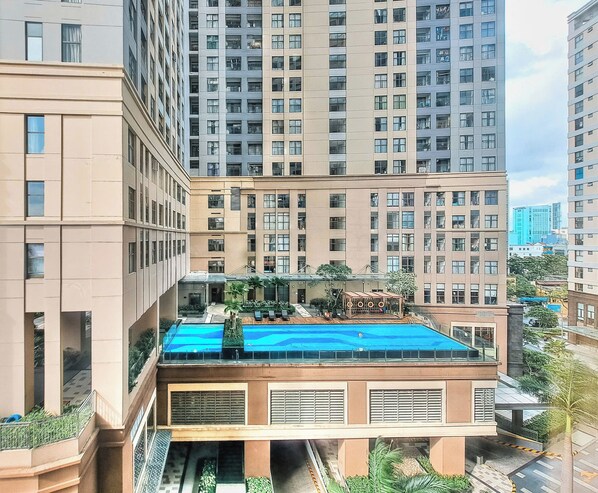 A high-rise building with a rooftop pool, multiple balconies, and a central courtyard with palm trees. - Spacious 4-bedroom condo with AC in soothing Thành phố Hồ Chí Minh (Thành phố Hồ Chí Minh)