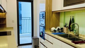 Una cucina moderna con mobili bianchi, un lavello in acciaio inossidabile e un piano di lavoro in legno.