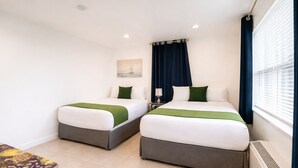 Ein Hotelzimmer mit zwei Betten, einem kleinen Tisch und einem Fenster mit Vorhängen.