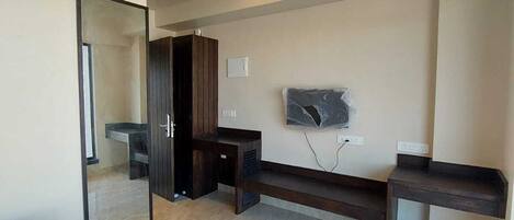 Un dormitorio moderno con cama, escritorio, televisor y armario.