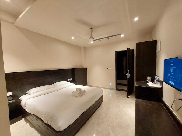 Een moderne hotelkamer met een groot bed, een flatscreen televisie, een bureau met stoel en een kledingkast.