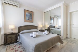 A hotel room with a bed, bedside lamps, a mirror, and a floral rug. - Villa Marbesa Beach (Marbella)