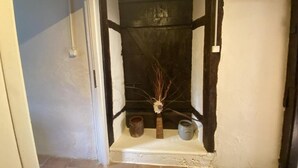 Un couloir étroit, avec une porte blanche sur la gauche et une porte en bois foncé sur la droite.