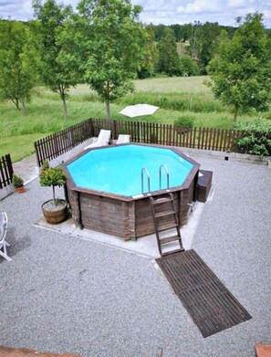 Une piscine rectangulaire dotée d’une terrasse en bois, entourée d’une clôture en bois, et une échelle permettant d’y accéder.