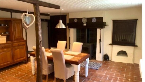 Un coin repas avec une table et des chaises en bois, une décoration en forme de cœur suspendue et une cheminée.