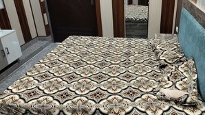 A bedroom with a patterned bedspread, a blue headboard, and a wardrobe.