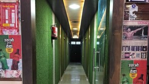 A corridor with green walls, a tiled floor, and posters advertising beverages.