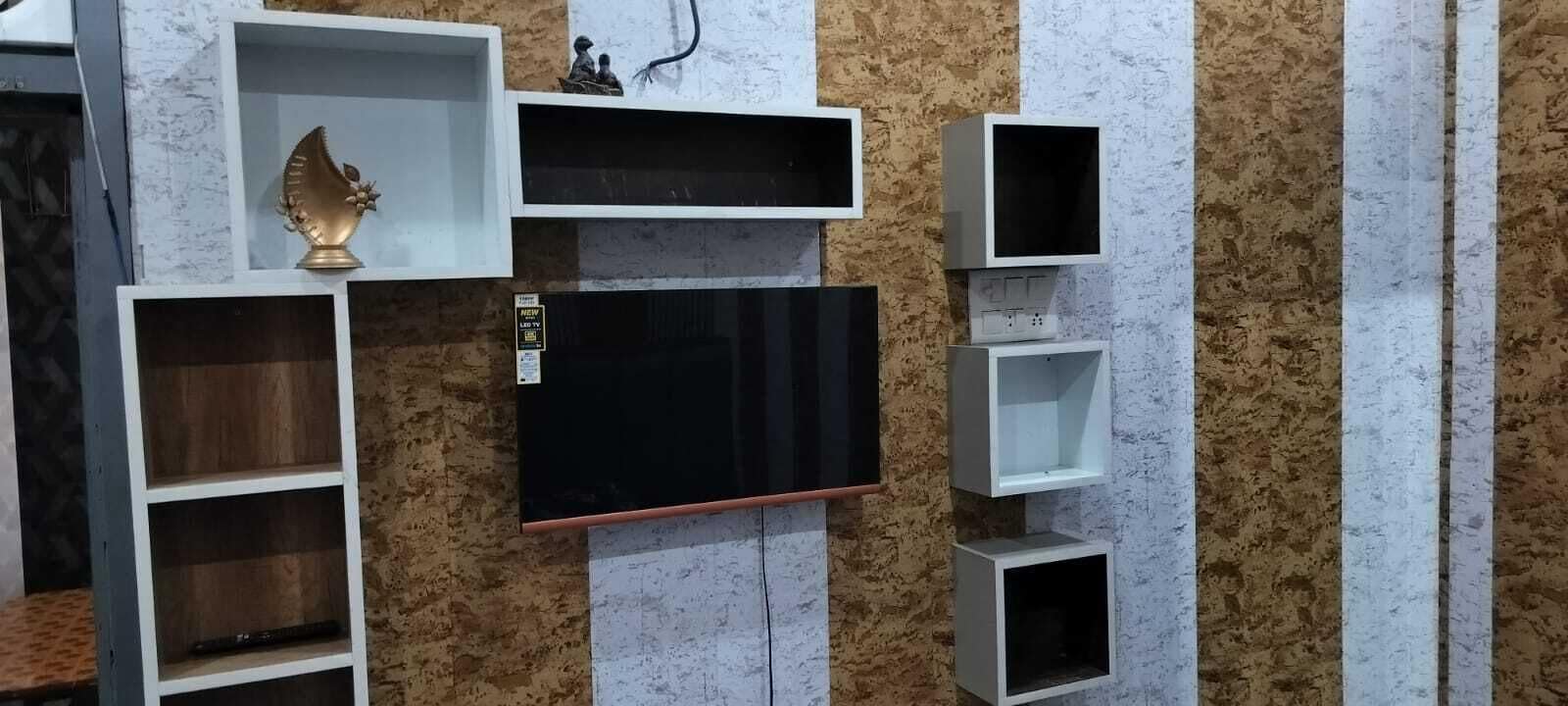 A wall-mounted TV with shelves and a decorative item.